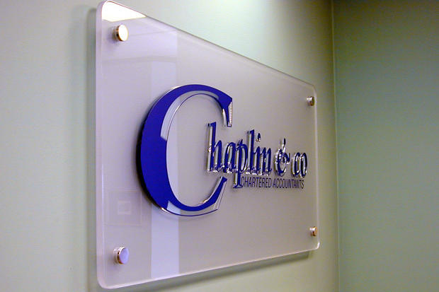 3D office sign for lobby reception area with raised acrylic letters on frosted glass acrylic panel raised off the wall on stainless steel mounts