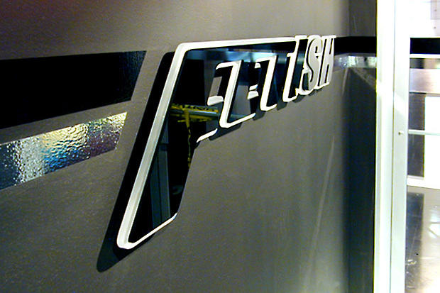 Illuminated laser cut frosted and black acrylic lobby sign raised off the reception wall on spacers.