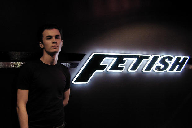 Man stands next to night club reception signs with laser cut acrylic and LED back lit logo lettering