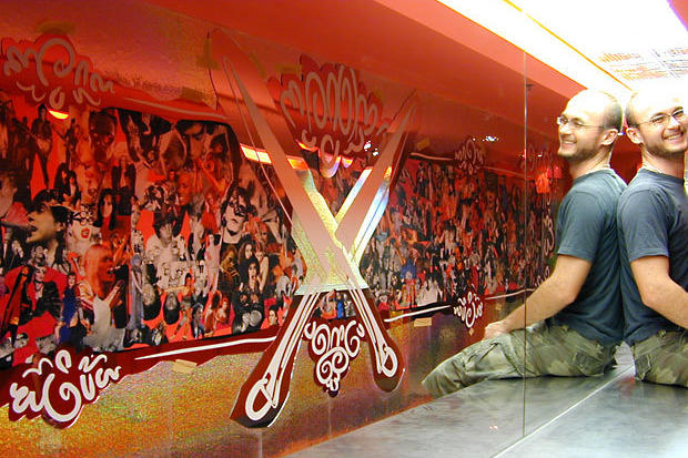 Installers in mirror reflection of laser cut wall art decor in night club bathroom
