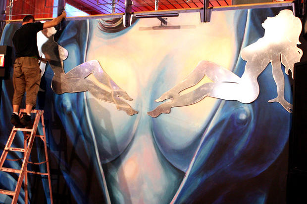Installers mounting laser cut mirror mud flap girl silhouettes on painted female torso as night club decor - Circa Toronto
