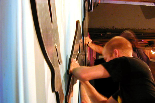Two installers remove protective coating from wall mounted laser cut mirrored acrylic decor in night club - Circa Toronto