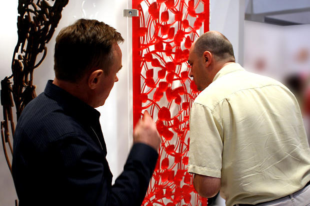 Tad Davinci - Designer showing laser cut panel to interested interior design show attendee - Art Signs Company.