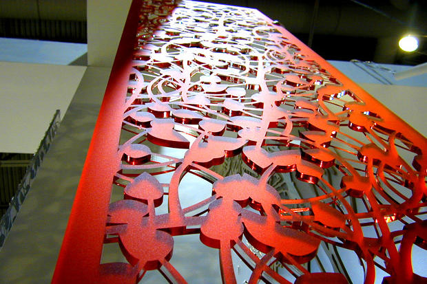 Red decorative laser cut screen reflecting light at exhibit showroom