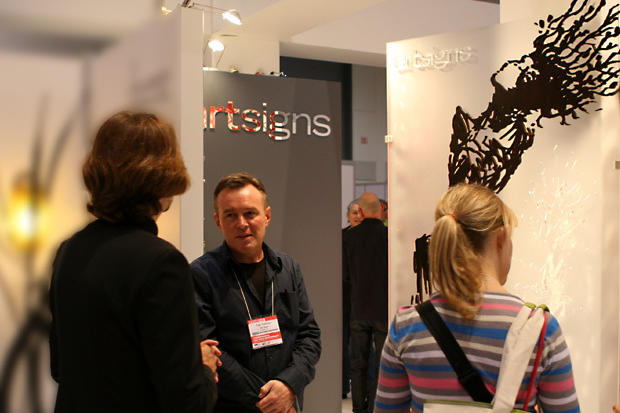 Designers discussing laser cut stained wood art panel on frosted acrylic background - Art Signs Company