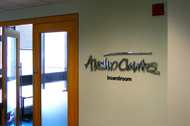 Laser cut stainless steel metal office signage lettering raised off business reception wall on spacers