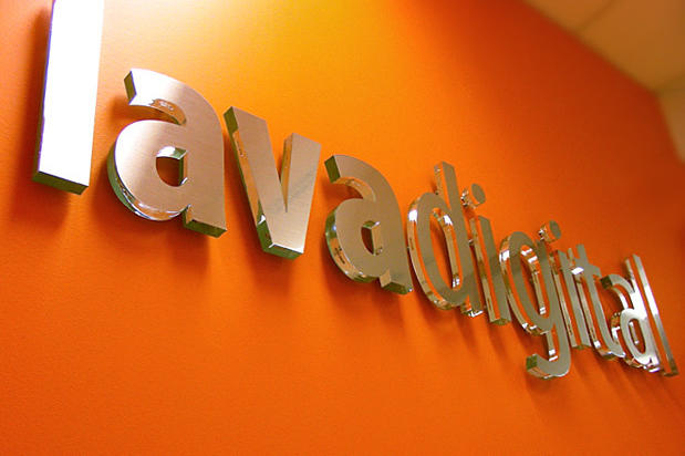 Lavadigital clear glass with brushed metal finish business wall signage in reception area. Signage made by Art Signs Company