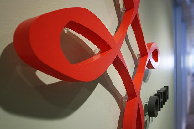 Office lobby signage with red colour dimensional laser cut acrylic letters raised off the reception area wall by Art Signs Company