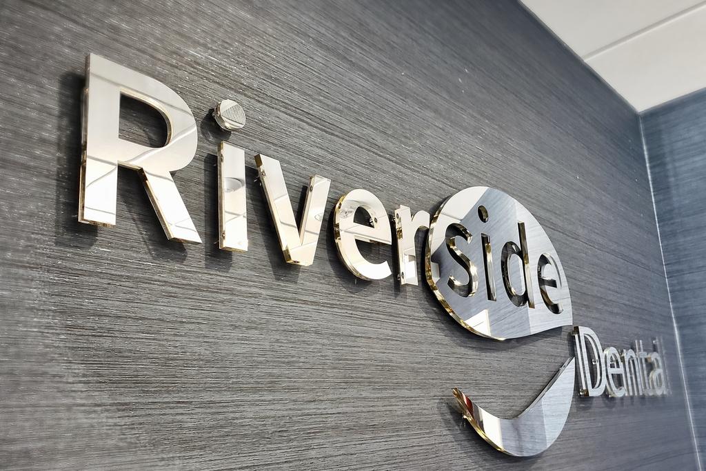 Mirrored acrylic letter sign installed in dentist office waiting room at Riverside Dental