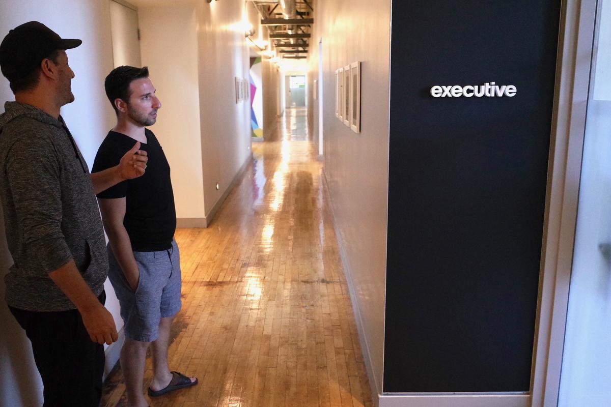 Kyle Bleiman and his partner at office door sign