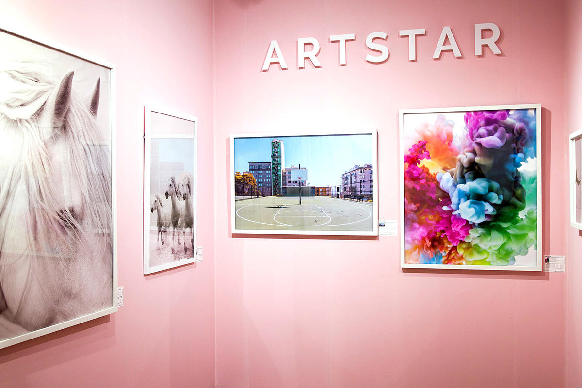 Art fair booth with paintings of horses, basketball court, and multi-colored ink with raised plastic sign letters mounted above.