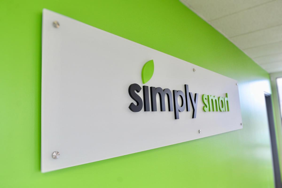 Green dimensional sign letters mounted on a white panel on a green reception wall