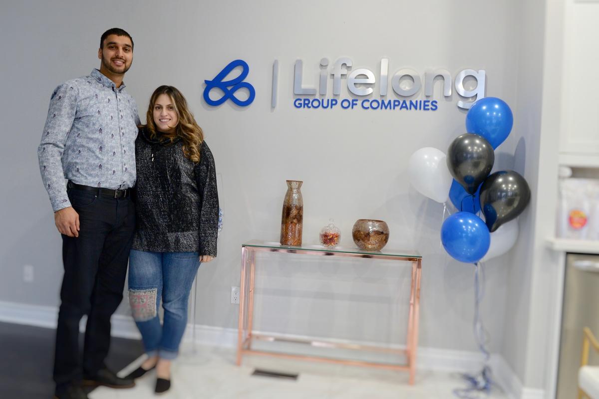 Absar Beg and Wife stand smiling next to new Real Estate Sales Center Lobby Sign on Opening Night