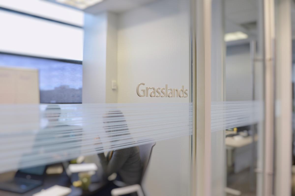 3D office door sign letters on Glass near sliding meeting room door that read Grasslands