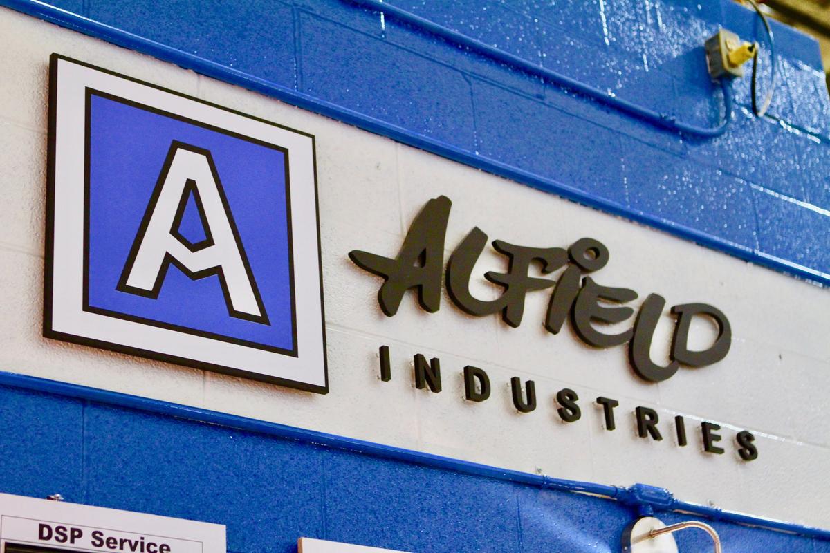 Custom 3D logo with black acrylic sign letters and custom color logo wall mounted to factory wall.