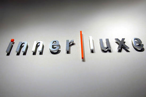 Shiny 3D metal office sign letters raised on risers off office lobby wall.