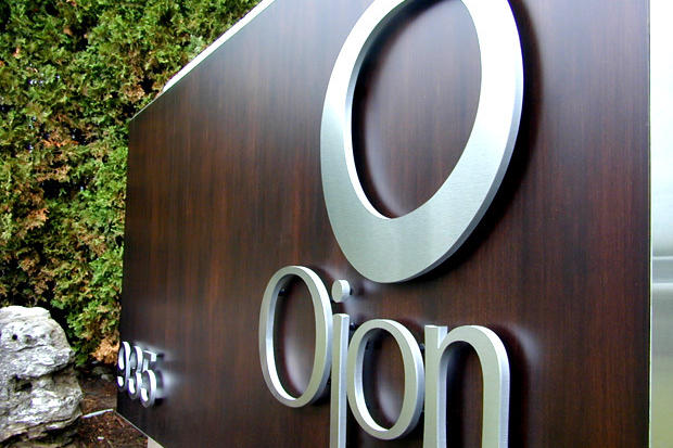 Brushed metal dimensional letter sign, Ojon and logo on stained wood panel for use as an exterior way finding