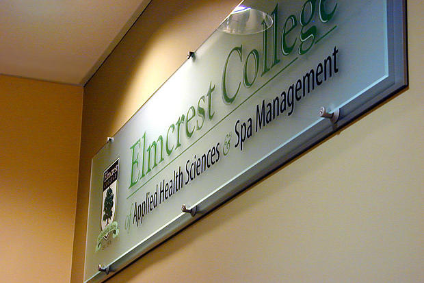 Illuminated acrylic glass panel office reception sign raised on decorative stainless steel mounts