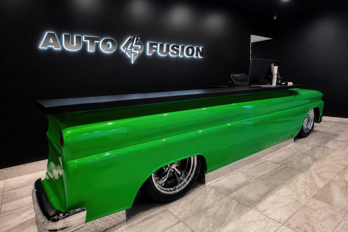 Custom 3D sign made of mirror chrome stainless steel with LED backlighting mounted behind reception desk for Auto Fusion.