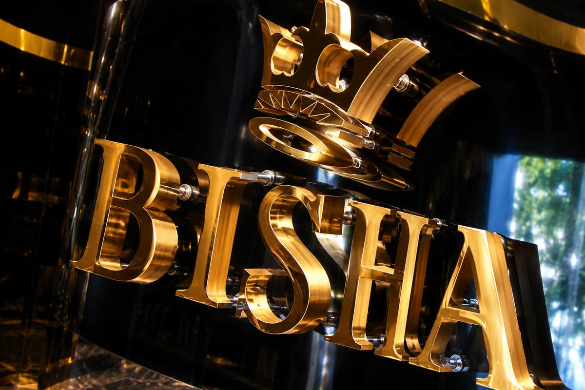 Close-up of the Bisha crown logo and gold mirror dimensional acrylic letters