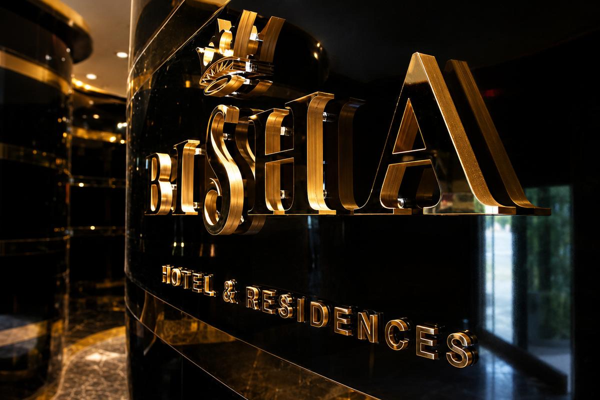 Angled view of Bisha gold mirror dimensional letters on a glossy black wall