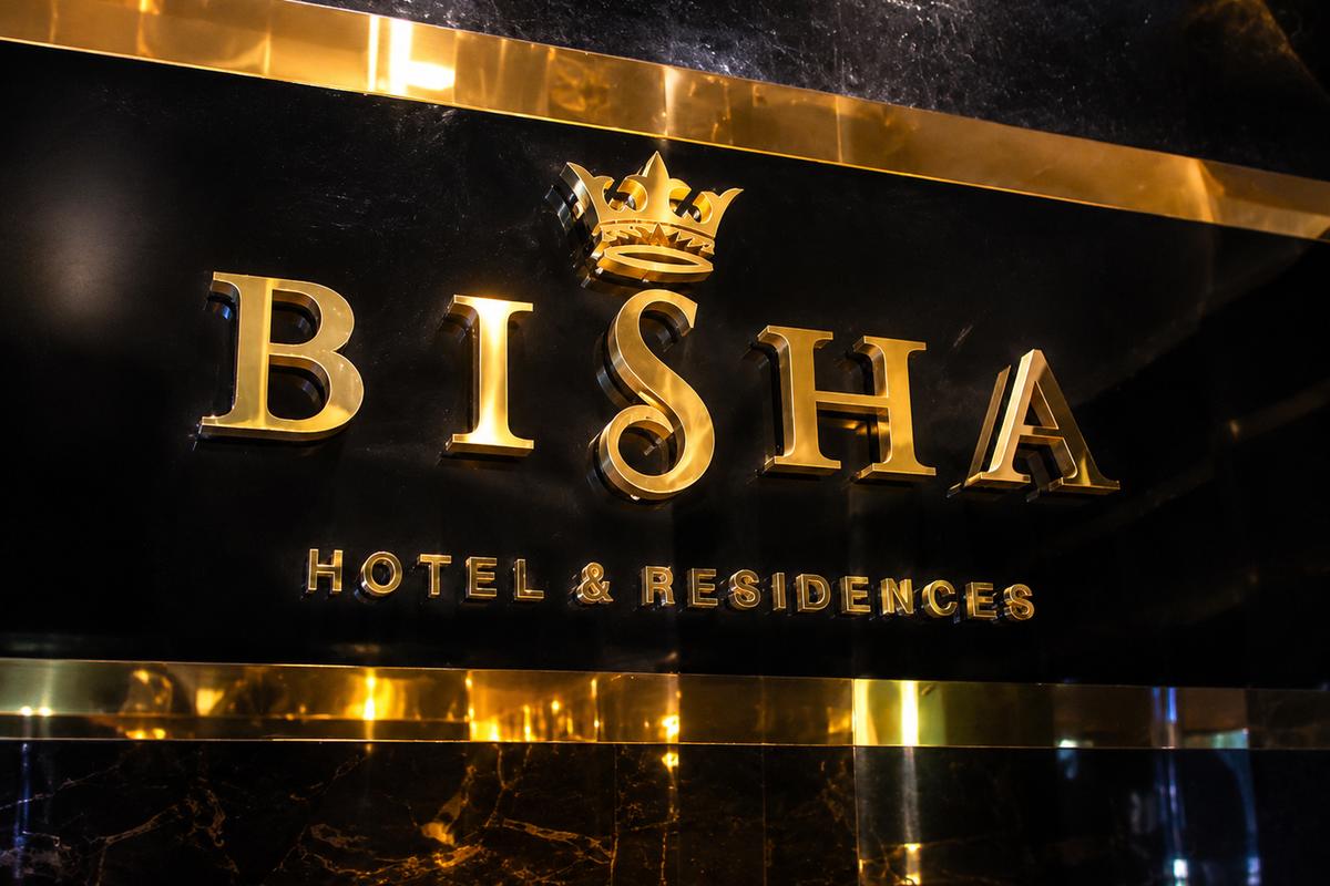 Front view of Bisha Hotel & Residences gold dimensional wall sign on glossy black stone