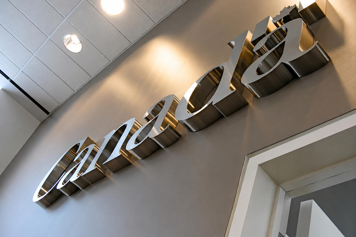 Side view of brushed stainless steel Canada wordmark sign with 3-inch deep dimensional letters mounted on a grey lobby wall