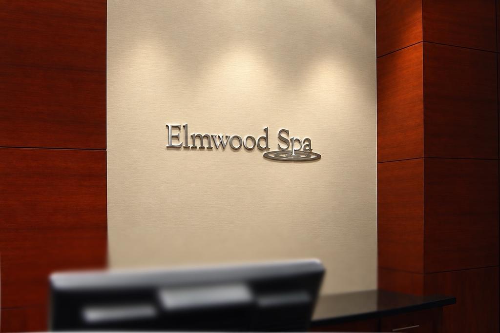 Brushed stainless steel Elmwood Spa wall sign behind a reception desk