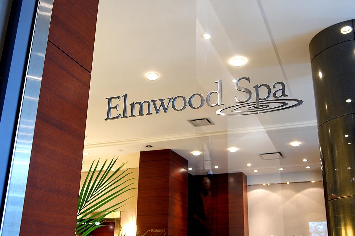 Brushed stainless steel Elmwood Spa letters mounted on a glass entrance with UV Glue