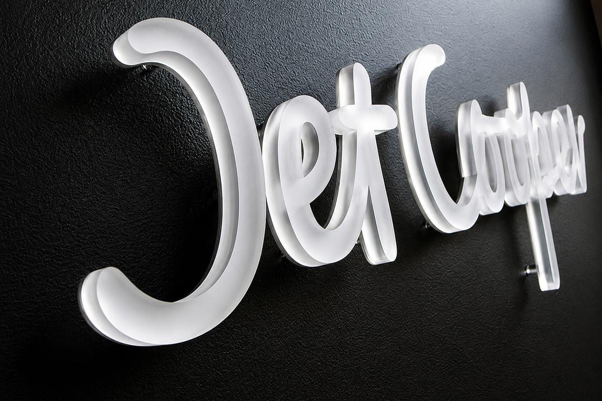 Left-angle view showing the thickness and frosted edges of a custom acrylic Jet Cooper office sign