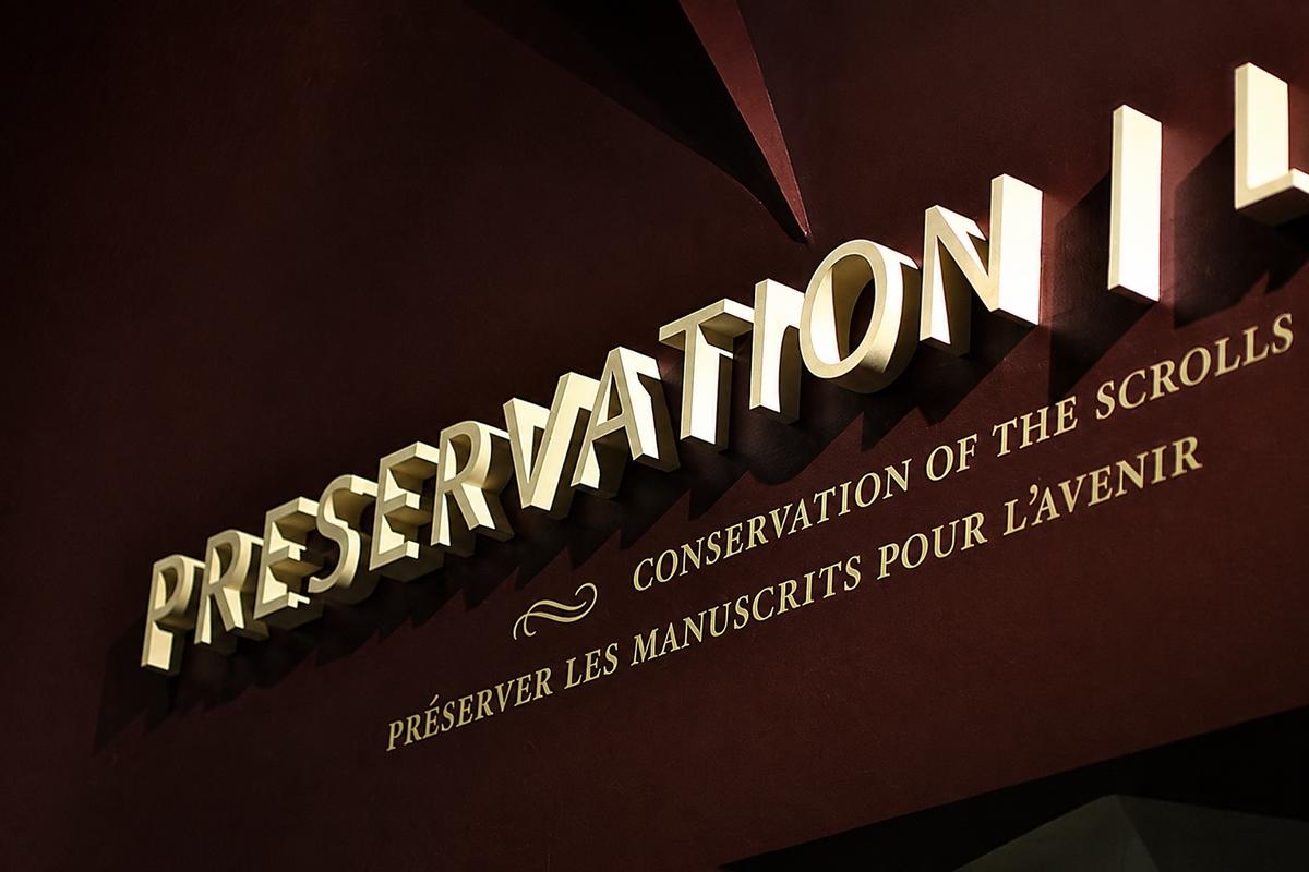 Cream dimensional Preservation lettering above bilingual text on a burgundy exhibition wall at the ROM in Toronto.