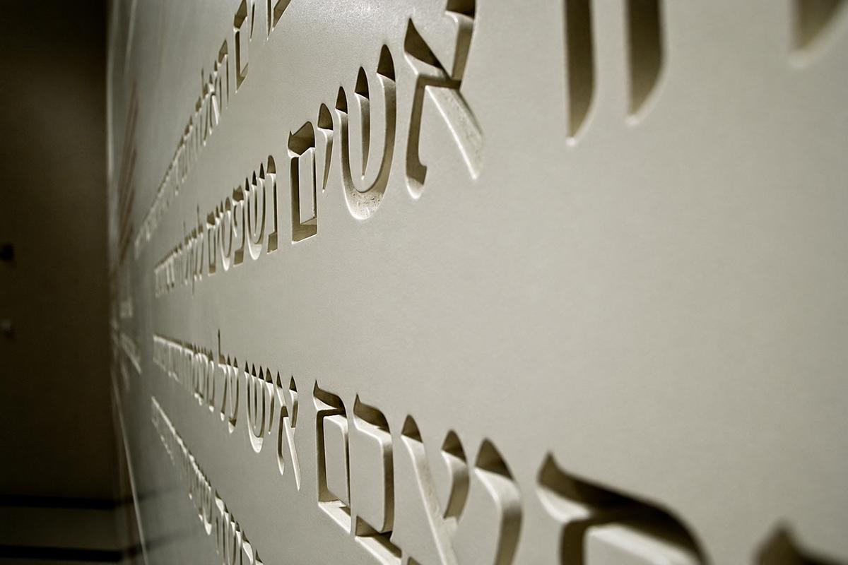 Close-up of Hebrew lettering cut into a beige MDF exhibition panel at the ROM in Toronto.
