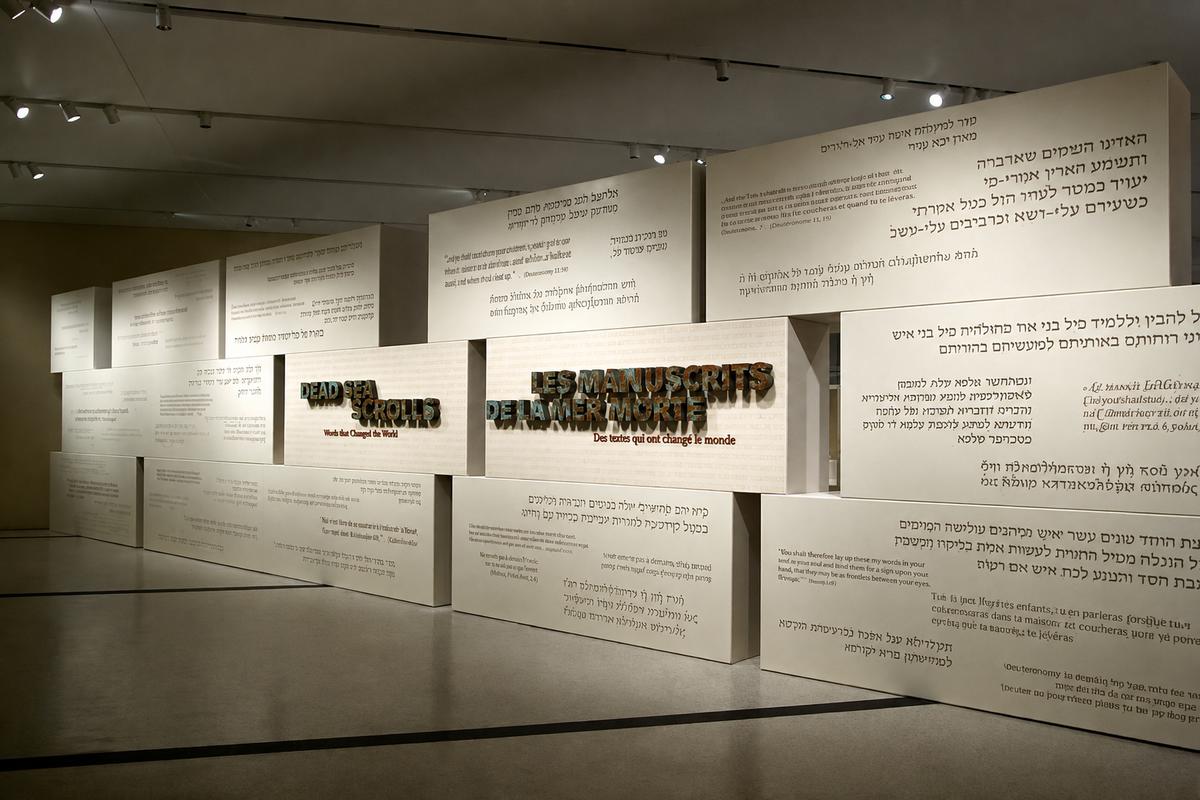 Wide view of bilingual Dead Sea Scrolls signs and staggered text panels at the Royal Ontario Museum in Toronto.