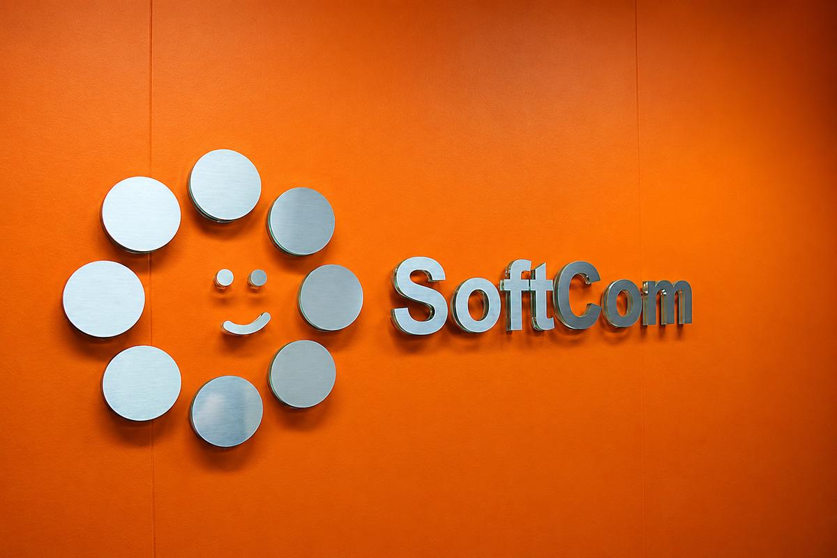 Full SoftCom logo wall sign on orange painted drywall with brushed metal faces and clear acrylic edges