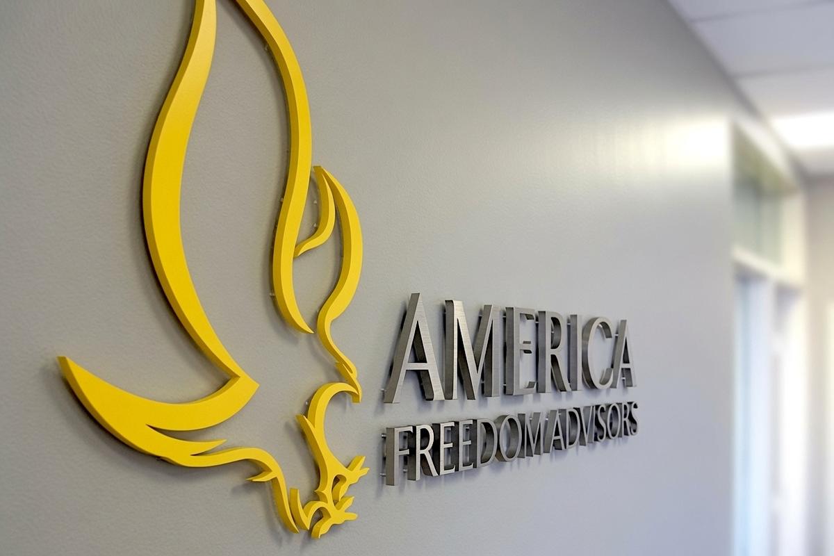 Angled view of the matte-yellow eagle and brushed nickel America Freedom Advisors logo