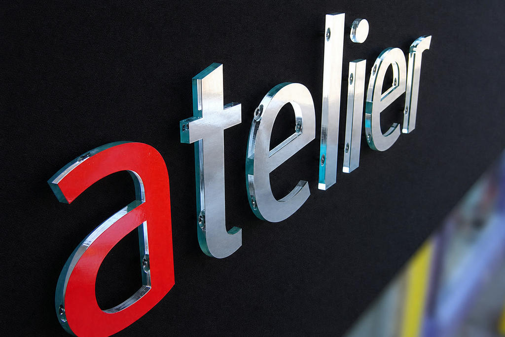 Close-up of Atelier acrylic logo letters with red and brushed-film aluminum faces