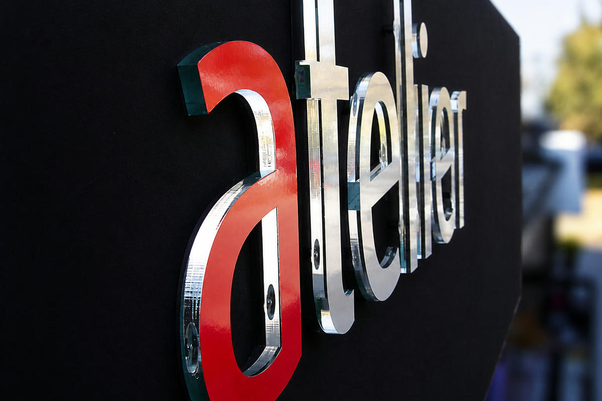 Side view of Atelier acrylic letters mounted to a black Sunbrella sign panel