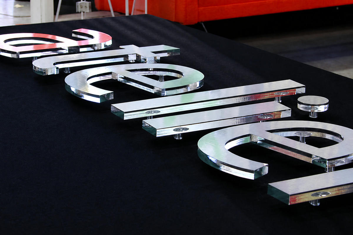 Atelier acrylic dimensional letters with brushed-film aluminum faces and clear green edges on black fabric