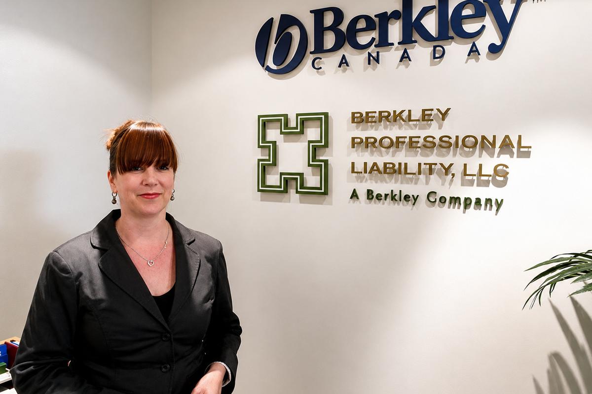 Woman beside Berkley Canada and Berkley Professional Liability dimensional office signs