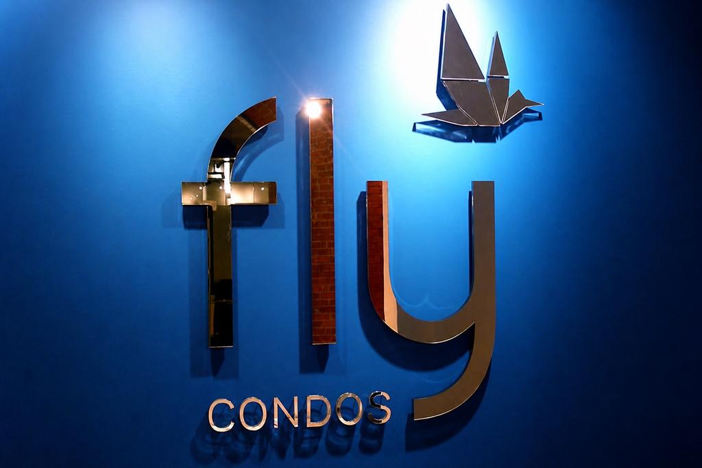 Front view of FLY Condos mirror acrylic wall logo with origami bird emblem