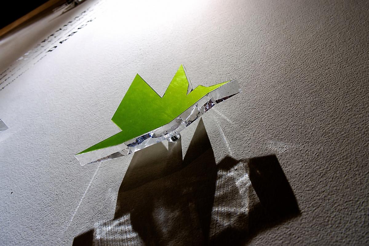 Green FLY Condos origami bird graphic on a clear acrylic wall display