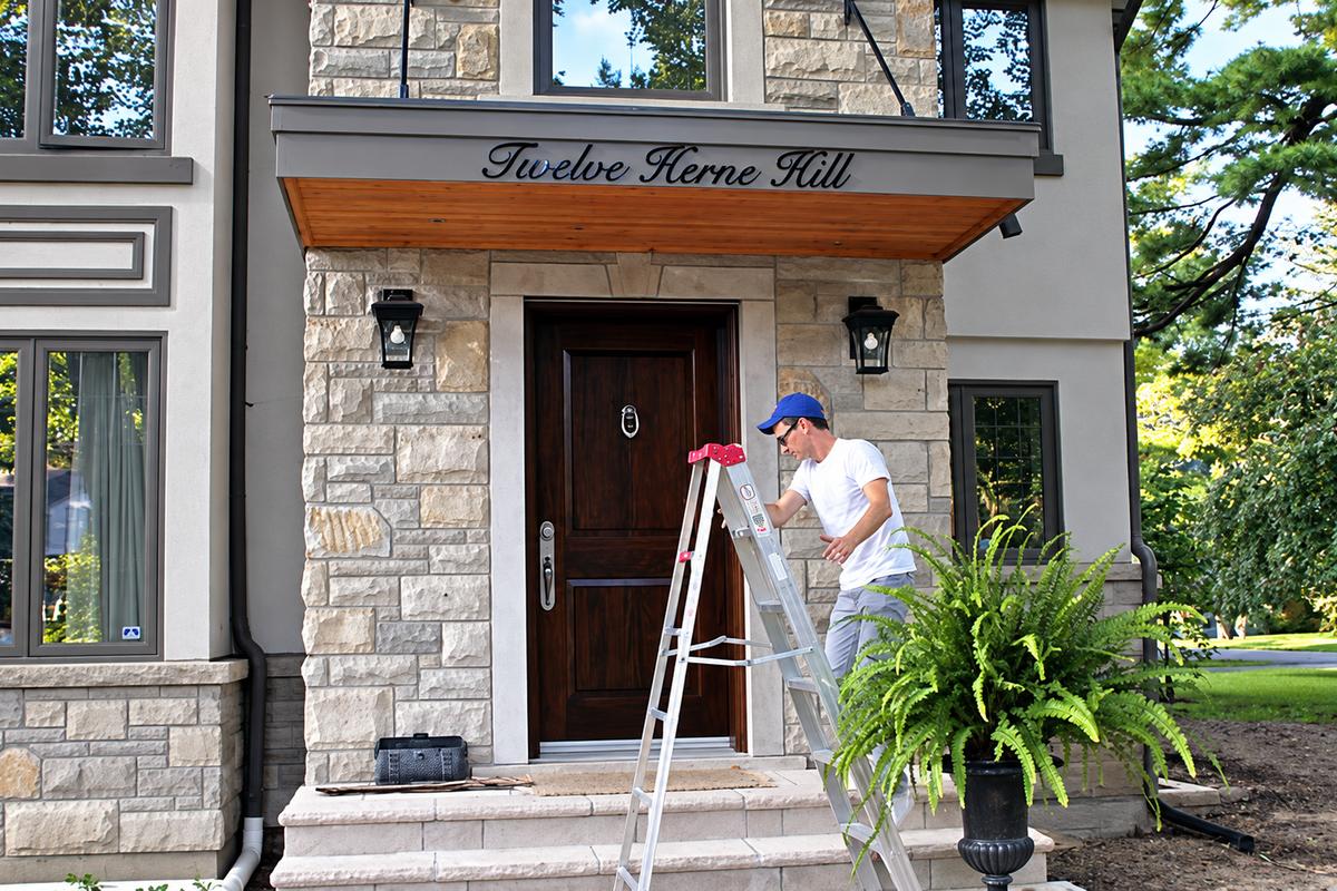 Installer beside Twelve Herne Hill acrylic address script over a stone home entrance