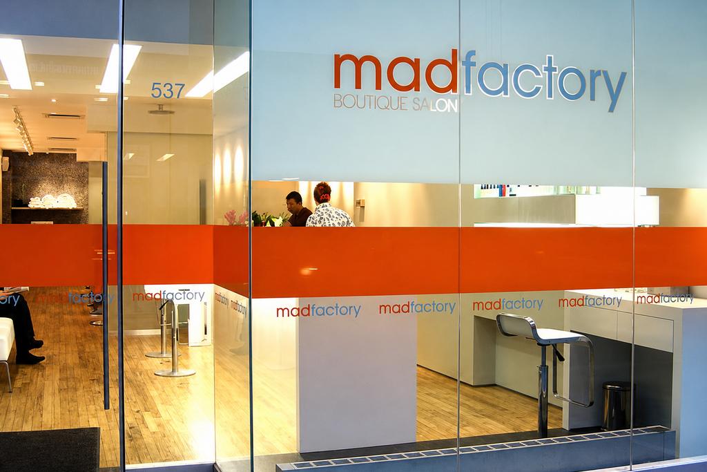 Madfactory salon storefront with frosted privacy film, orange vinyl bands and logo graphics