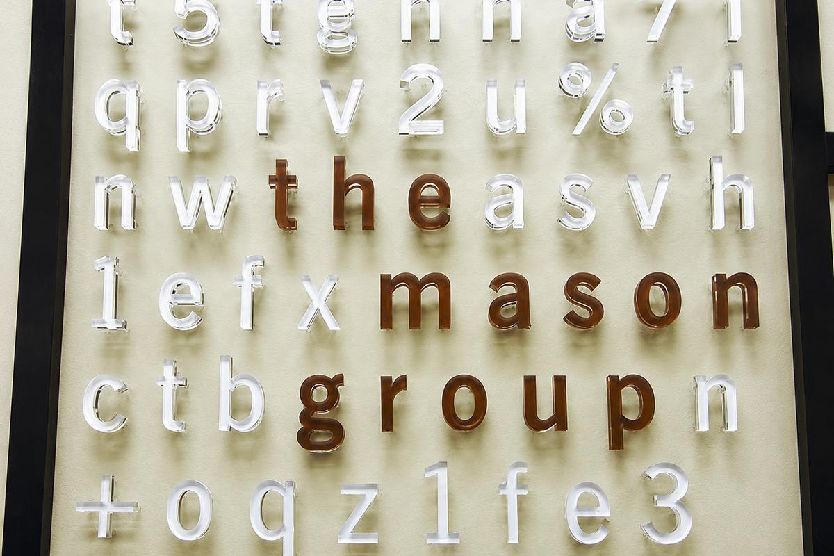 Raised acrylic with metal effect office signage reflecting light and casting shadow on reception area wall - Art Signs Company