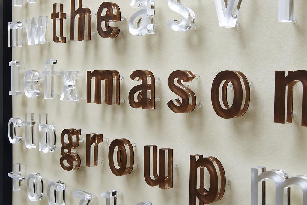 Raised decorative frosted acrylic signage letters as lobby sign behind desk in reception area - Art Signs Company