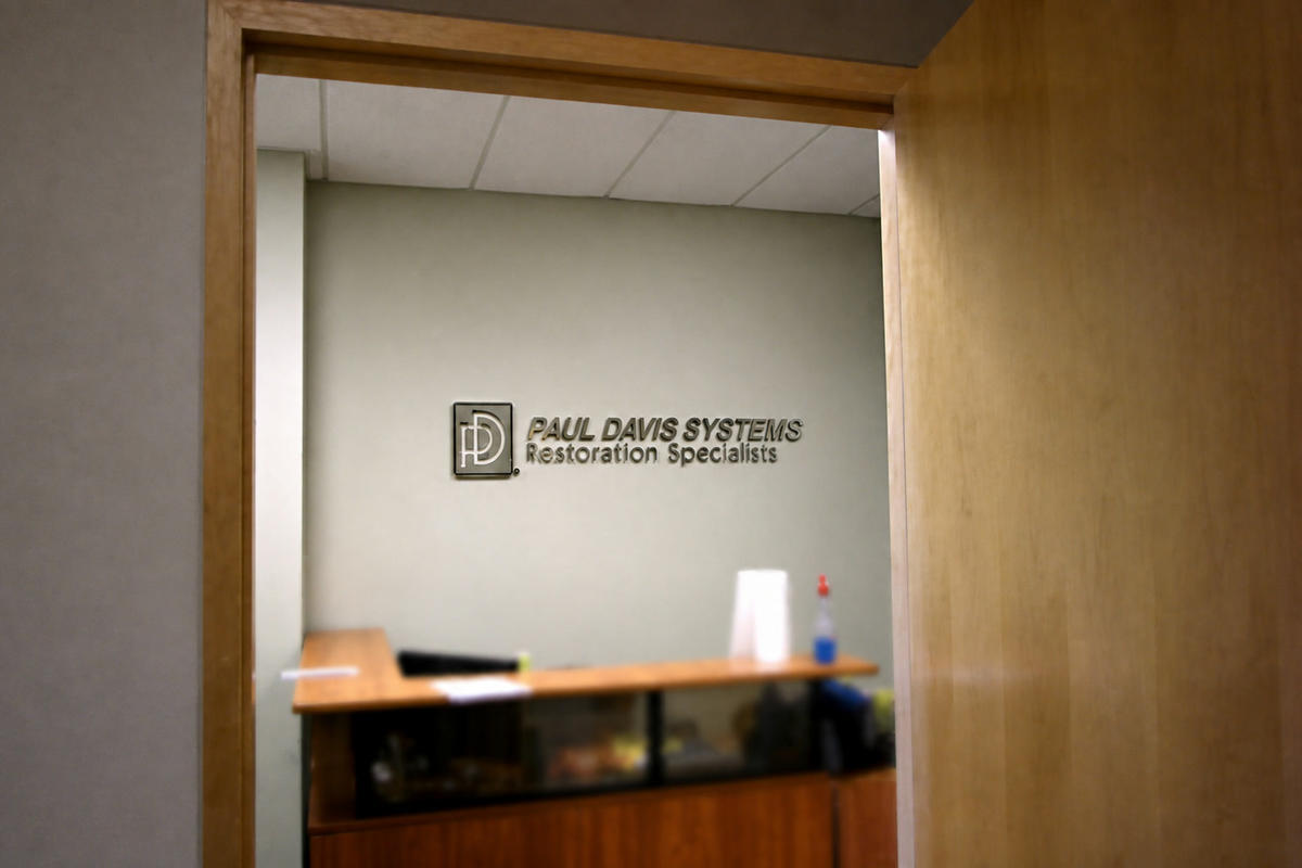 Paul Davis brushed nickel reception wall sign viewed through a wood doorway