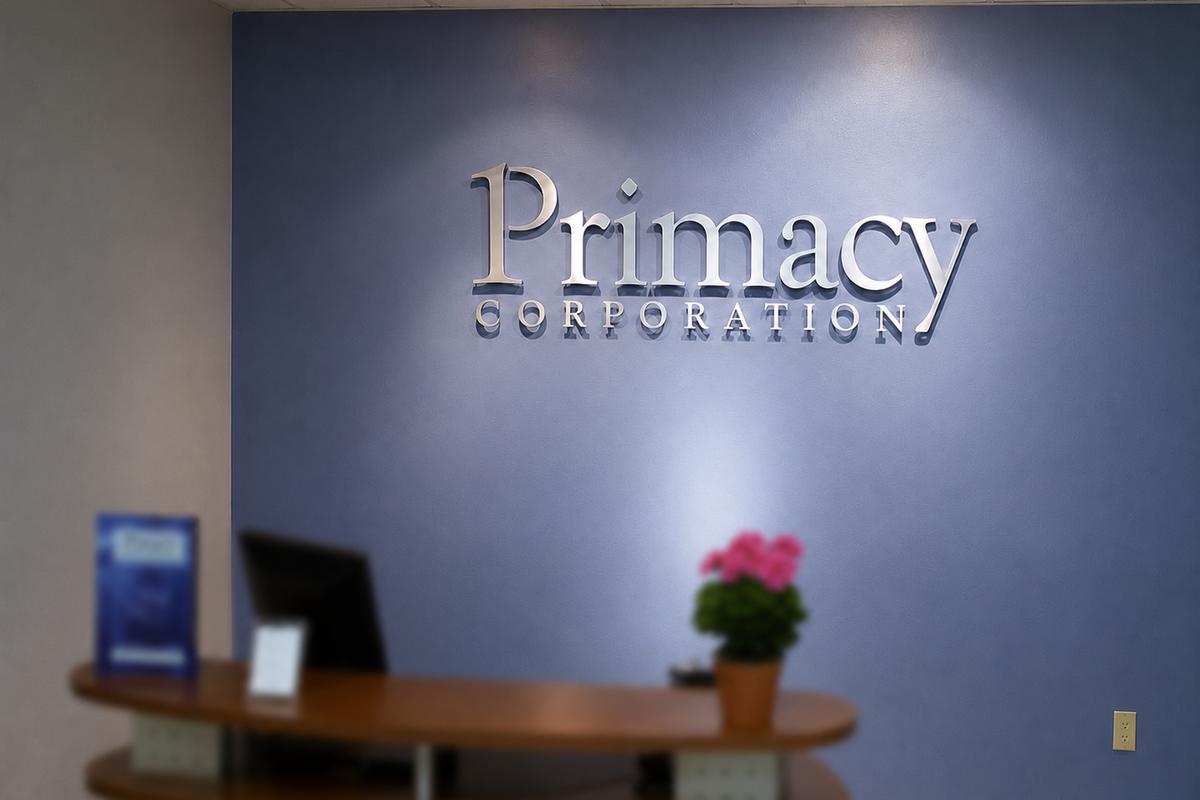 Primacy Corporation clear acrylic office sign with brushed aluminum faces on a blue wall