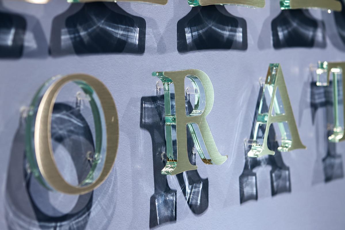 Close-up of clear acrylic logo letters with brushed aluminum faces and green edges