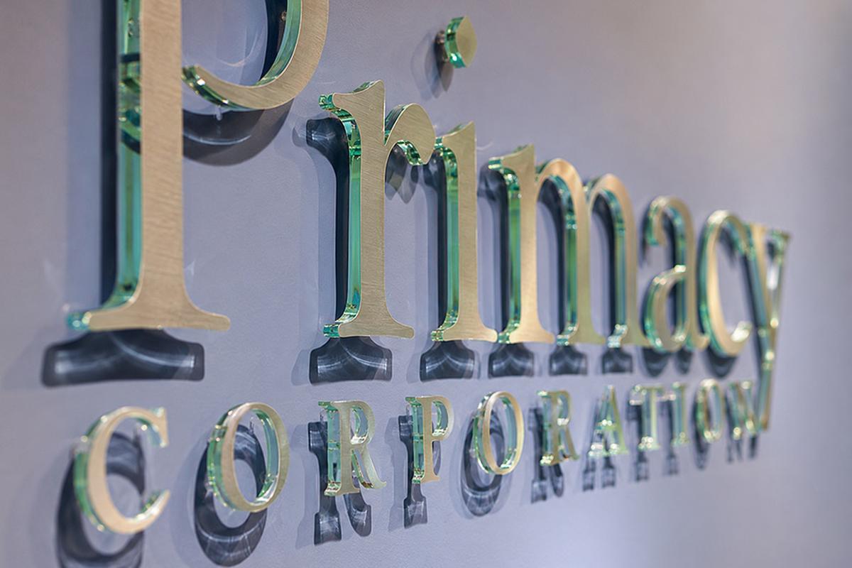 Angled side view of Primacy acrylic office sign with green edges and metal faces