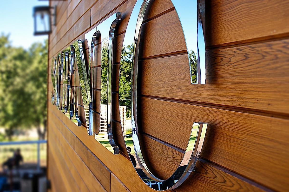 Side view of SCENIC letters showing 3/4-inch clear acrylic body, 1/4-inch mirror laminate and dimensional gap off the wood